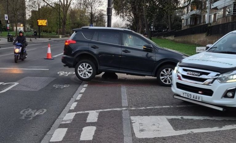 A driver's car on a bollard on the pavement of Brixton Hill at Dunbarton Rd