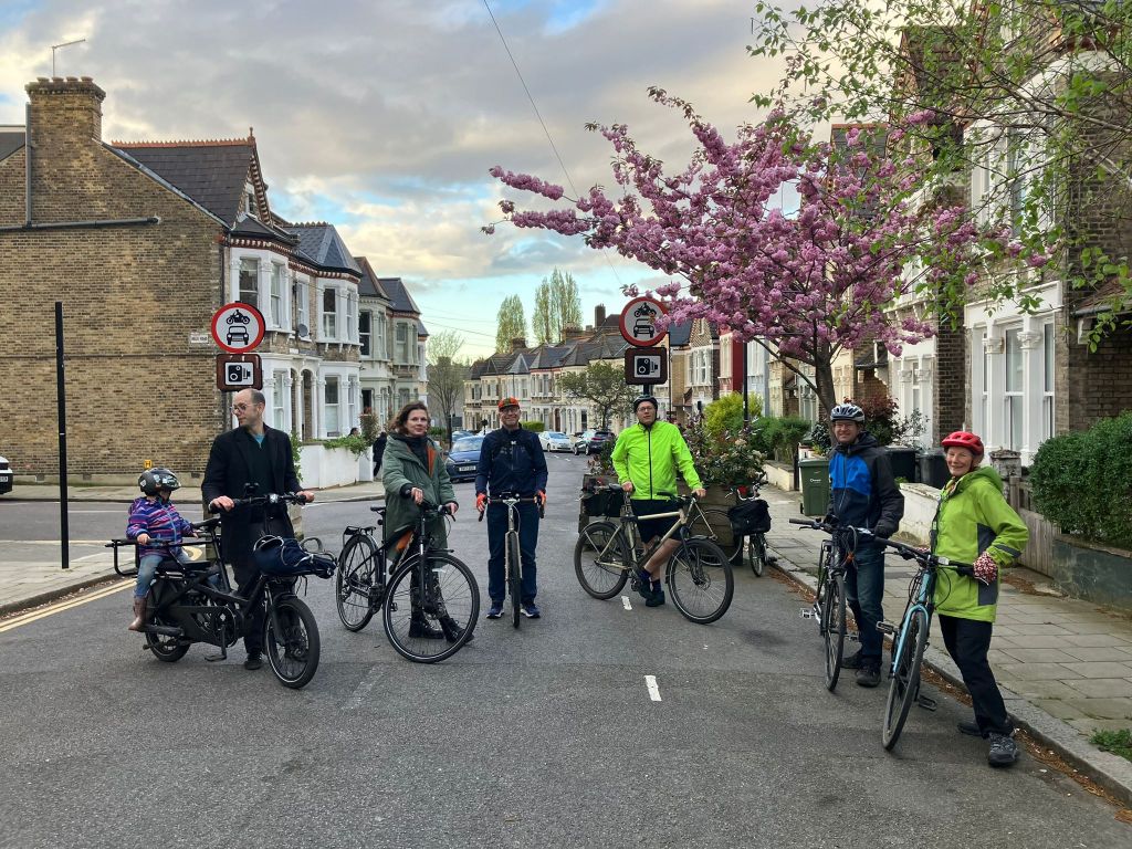 A group of people with their bikes under cherry blossom at the traffic filter on Leander Road